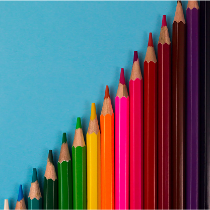 Foto van kleurpotloden in kleuren van de regenboog, liggend op een blauwe achtergrond